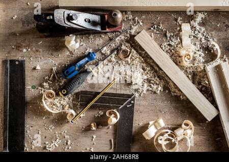 Banco di lavoro con una varietà di utensili a mano in una falegnameria o ebanisteria workshop compresi scalpelli, cacciaviti, nastro di misurazione, matita, righello Foto Stock