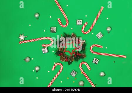 Composizione di natale su sfondo verde. Xmas frame con candy canes, bacche rosse. Vista superiore, piatto laici. Foto Stock