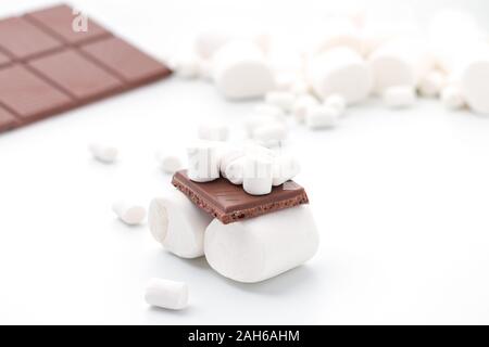 Un sandwich di piccole e grandi marshmallows e cioccolato al latte su una barra di cioccolato sullo sfondo, isolato Foto Stock