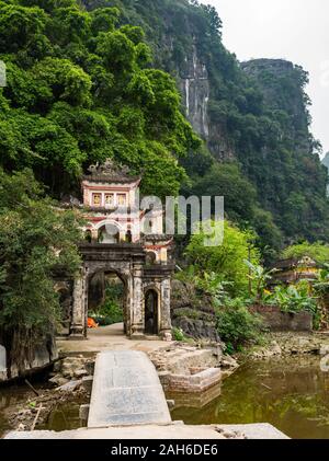 Ingresso al vietnamita tempio Buddista oltre il ponte ad arcate, Bich Dong Pagoda, Tam Coc, Ninh Binh, Vietnam Asia Foto Stock