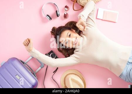 Bellezza donna asiatica sorridenti felicemente e giacente sul piano di colore rosa. Vista superiore Foto Stock