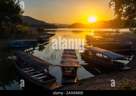 Barche di viaggio parcheggio sul serbatoio durante il tramonto nelle zone rurali della Thailandia Foto Stock