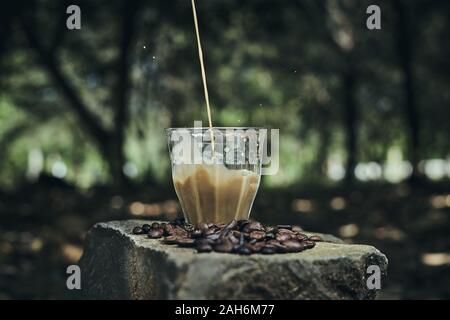 Un bicchiere di latte macchiato di caffè con sfondo naturale Foto Stock