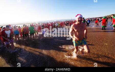 Circa 1.200 persone hanno preso parte all'annuale del giorno di Natale Macmillan Caring Bianco Natale Dip 25/12/2019. La gente in costume e su una luminosa mattina di sole corse in mare su Boscombe fronte mare. La raccolta di fondi per la cura Macmillian localmente le cure palliative unità in Christchurch, questo evento è cresciuto nel corso degli anni. Circa un quarto di milione di è stata sollevata poiché gli eventi inizi. Foto Stock