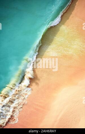 Vista da sopra, splendida vista aerea di alcune onde si infrangono su di una bella spiaggia durante il tramonto. Kelingking beach, Nusa Penida, Indonesia. Foto Stock