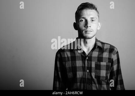 Ritratto di giovane hipster uomo contro uno sfondo grigio Foto Stock