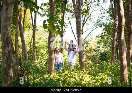 Asian i genitori e il bambino divertirsi all'aperto a piedi nei boschi Foto Stock