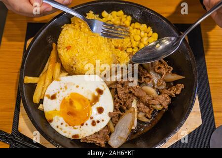 Piatto di gustosi piatti sfrigolanti stir-fried pasto sul piatto di ferro Foto Stock