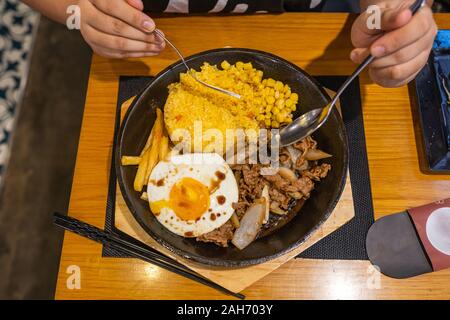 Mangiare umani sfrigolanti carni bovine sisig riso sul piatto di ferro Foto Stock