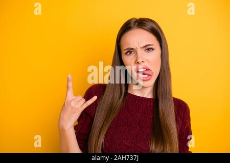 Close up foto di carino gioventù facendo segni clacson ingannare indossando maroon, pullover isolate su sfondo giallo Foto Stock