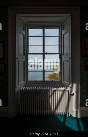 Interno di una vecchia ed elegante casa scozzese, con una finestra che si affaccia sulla costa e le isole lontane Foto Stock