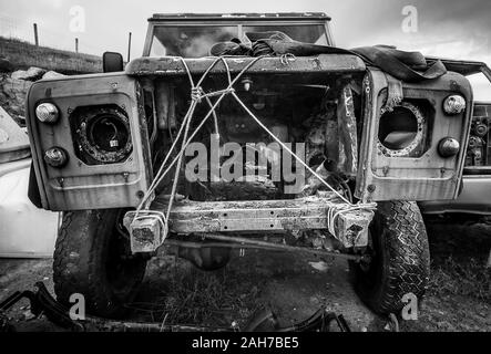 Bianco e nero primo piano di un vecchio e relitto vettura 4x4 manca il motore e i fari e tenuto insieme ad una fune Foto Stock