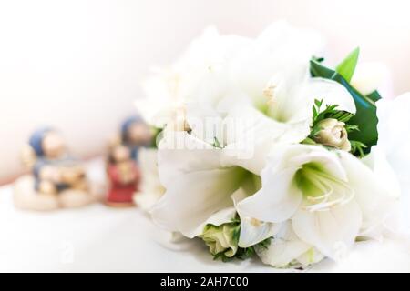 Primo piano di un bouquet di nozze bianco composto da gigli bianchi giacenti su un tavolo contro uno sfondo bokeh Foto Stock