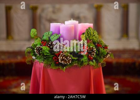 Primo piano sulla corona di Avvento con candele rosa come tradizionali decorazioni di Natale nella chiesa Foto Stock