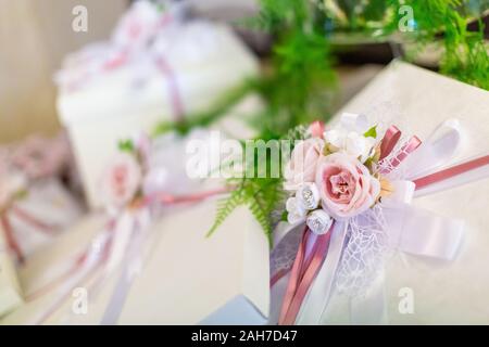 Decorazioni per matrimoni, con un bouquet di rose rosa in primo piano e scatole regalo fuori fuoco sullo sfondo Foto Stock