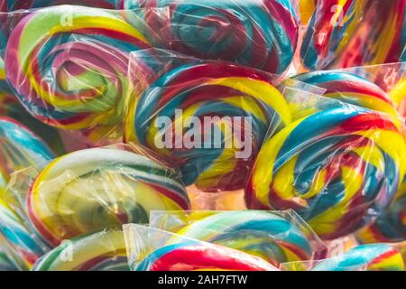 Gruppo di brillanti lecca lecca colorati nel display per la vendita in un negozio di caramelle in singoli imballaggi in plastica, il fuoco selettivo. Foto Stock