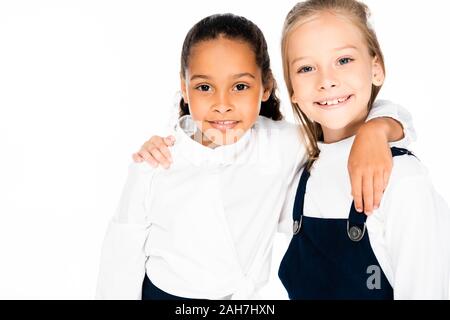 Due lieti multiculturale di studentesse abbracciando e sorridente in telecamera isolato su bianco Foto Stock