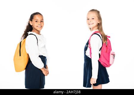 Due allegro multiculturale di studentesse con zaini guardando la telecamera isolato su bianco Foto Stock