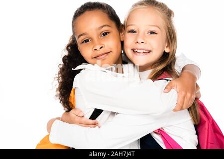 Due lieti multiculturale di studentesse abbracciando mentre sorridente in telecamera isolato su bianco Foto Stock