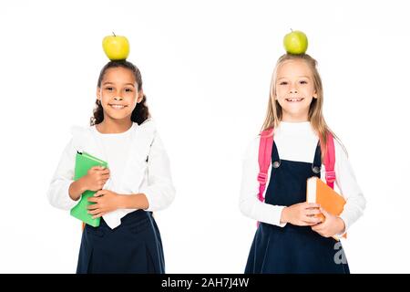 Due allegro multiculturale di studentesse con mele su capi azienda libri isolato su bianco Foto Stock