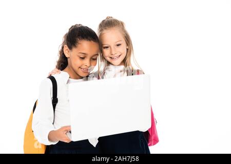 Due allegro multiculturale di studentesse sorridere mentre utilizzando computer portatile isolato su bianco Foto Stock