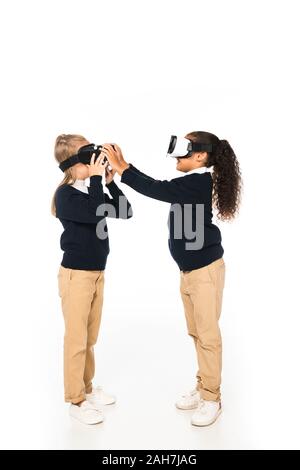 Lunghezza piena vista di due amici multiculturale utilizzando la realtà virtuale auricolari su sfondo bianco Foto Stock
