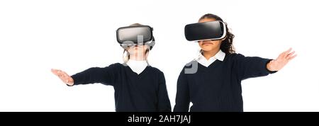 Panoramica di due studentesse multiculturale utilizzando la realtà virtuale auricolari isolato su bianco Foto Stock