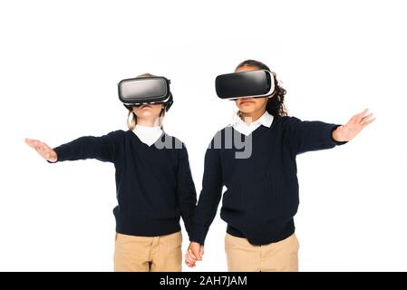 Due studentesse multiculturale tenendo le mani mentre si utilizza virtial realtà auricolari isolato su bianco Foto Stock