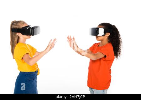 Due amici multiculturale guardando ogni altro mentre utilizzando la realtà virtuale auricolari isolato su bianco Foto Stock