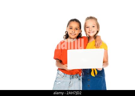 Due felici amici multiculturale di sorridere alla telecamera mentre utilizzando laptop insieme isolato su bianco Foto Stock