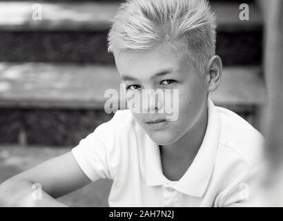 Monocromatico (bianco e nero) ritratto di bella bionda carino undici vecchio ragazzo (adolescente) seduto sulle scale outdoor.Growing su, chilhood, separazione Foto Stock