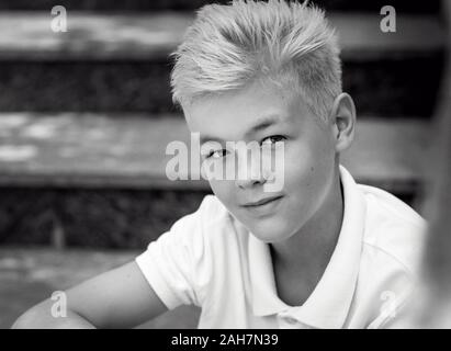 Monocromatico (bianco e nero) ritratto di bella bionda carino undici vecchio ragazzo (adolescente) seduto sulle scale outdoor.Growing su, chilhood, separazione Foto Stock