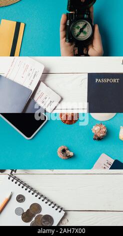 Collage di passaporti con carte di imbarco, conchiglie, denaro, smartphone, bussola in mano femmina e notebook con matita su blu e bianco in legno indietro Foto Stock