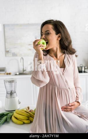 Felice donna incinta squisito vicino le banane Foto Stock