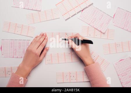 Vista parziale di donna numeri di marcatura su biglietti della lotteria sul tavolo bianco Foto Stock