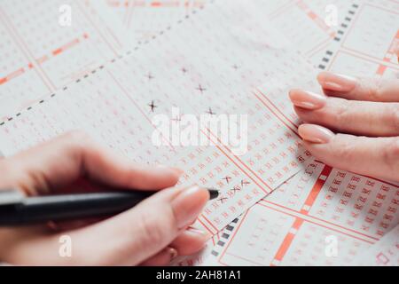 Vista ritagliata della donna numeri di marcatura in biglietti della lotteria Foto Stock