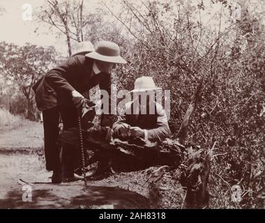 ZimbabweRhodesiaZambia, tre uomini europei pesce persico sul bordo di una scogliera ammirando una vista delle cascate Victoria. 12 Novembre 1910.Note da stampato un itinerario di visita:sabato novembre 128.20 A.M. Victoria Falls. Arrivare al ponte sul Zambesi. Vedere Victoria Falls, banca del Nord. Abiti informali o kaki uniforme è indossata durante tutta in Rhodesia, 1910. 1995/076/1/4/1/47. Foto Stock