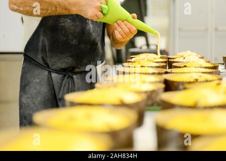 Chef pastoso chef adulto forte preparare e decorare panettone per la cottura , un dolce pane natalizio tipico di Milano Foto Stock