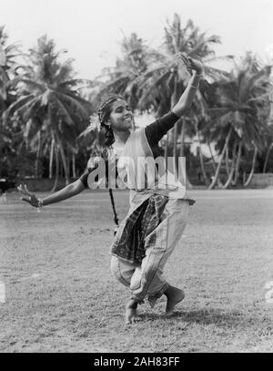 Sri LankaCeylon, Sri Lanka tamil ballerino. Una giovane donna Tamil sorrisi come lei esegue una danza tradizionale all'esterno. I suoi capelli sono intrecciati in una lunga treccia e indossa il costume tradizionale. La didascalia recita "ballerino TAMIL - JAFFNA', 1957. 2005/010/1/3/44. Foto Stock