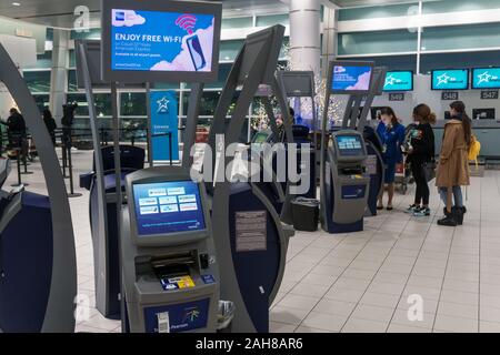 Lester Pearson airport area check-in, Toronto, Dicembre 2019 - Passeggeri essendo assistito a sé i chioschi di check-in da un dipendente della compagnia aerea Foto Stock