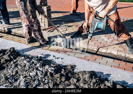 I lavoratori di cui pavimentazione in lastre. Due lavoratori laici di lastre per pavimentazione. Foto Stock