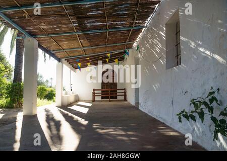 Ingresso con Palm tree della chiesa abadoned Ermita de Sant Antoni y Sant Jaume nel cappuccio Blanche con drammatica raggi solari, Altea, Spagna Foto Stock