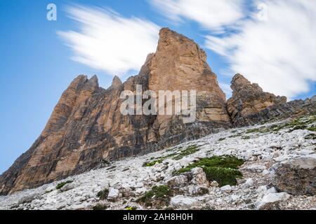 Ampia vista dal basso delle tre cime di Lavaredo, nelle Alpi italiane, sotto un cielo blu con nubi Foto Stock