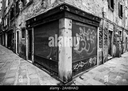 Vista grandangolare in bianco e nero di una Cornershop abbandonata, con le sue persiane ricoperte di graffiti Foto Stock