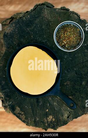 Delizioso formaggio Provolone argentino formaggio filato (Provoleta) con spezie su un vecchio log su di una superficie di legno, provincia di Buenos Aires, Argentina. Per esterno Foto Stock