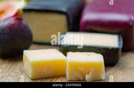 Mini nero e rosso scuro cerata formaggi cheddar realizzato da ovest paese latte e secolare e metodi in Inghilterra da vicino Foto Stock