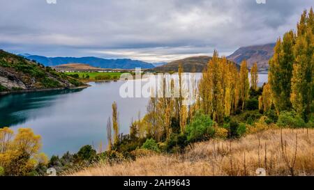 Una vista panoramica di un bellissimo lago di acqua dolce in autunno, circondato da dolci colline e terreni agricoli rurale, sull'Isola del Sud della Nuova Zelanda. Foto Stock