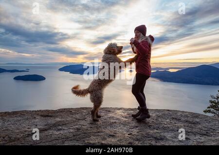 Ragazza avventurosa escursionismo sulla cima di una montagna con un cane Foto Stock