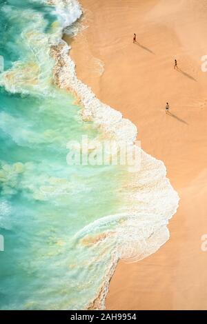 Vista da sopra, splendida vista aerea di alcuni turisti giocando, prendere il sole e nuotare su una bellissima spiaggia bagnata da un mare turchese durante il tramonto. Foto Stock