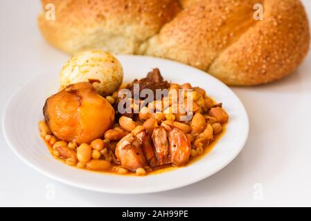 Challah Shabbat pane e hamin cholent o in ebraico - Sabato il cibo tradizionale sul tavolo bianco in cucina.Vista dall'alto. Foto Stock